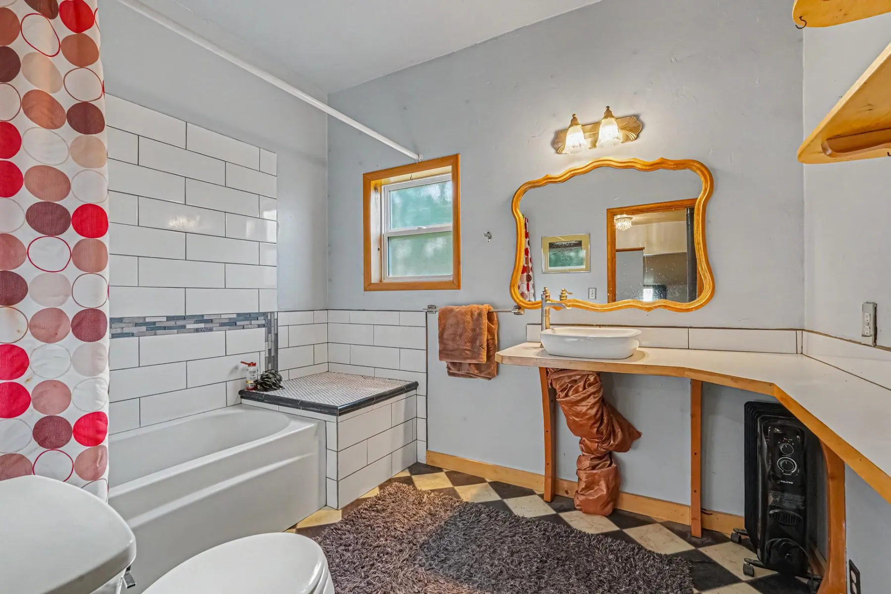 Renovated bathroom with subway-tiled tub surround, vessel sink and framed mirror