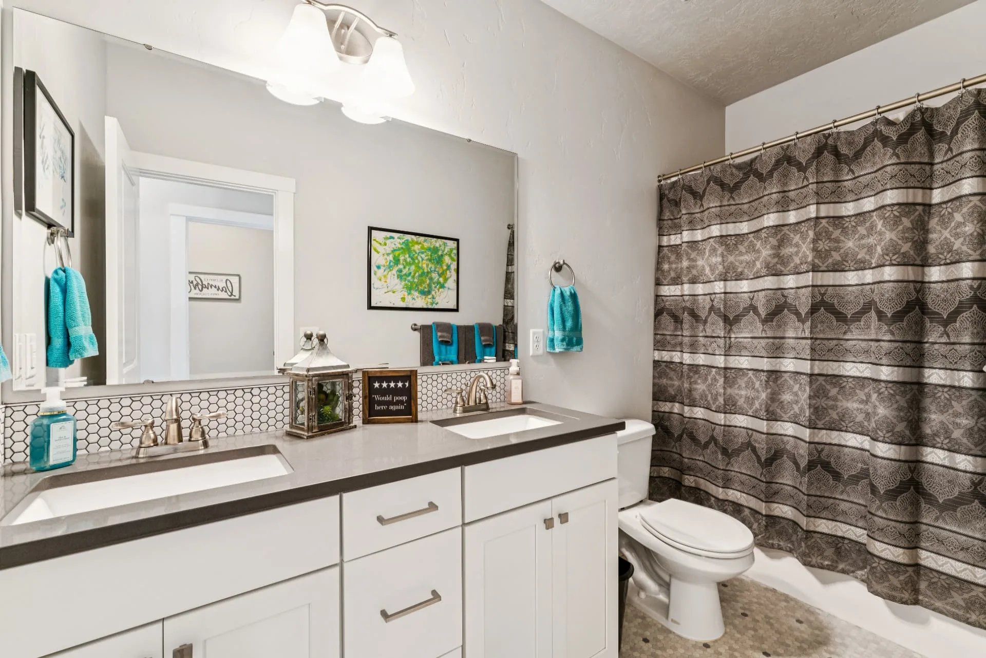 Second bathroom with a dual-sink vanity, large mirror, tile backsplash and a tub and shower behind a curtain