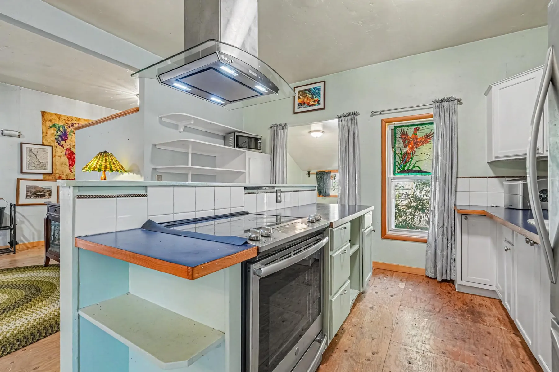 Kitchen with stainless-steel range, island hood, tile counters and a stained-glass window