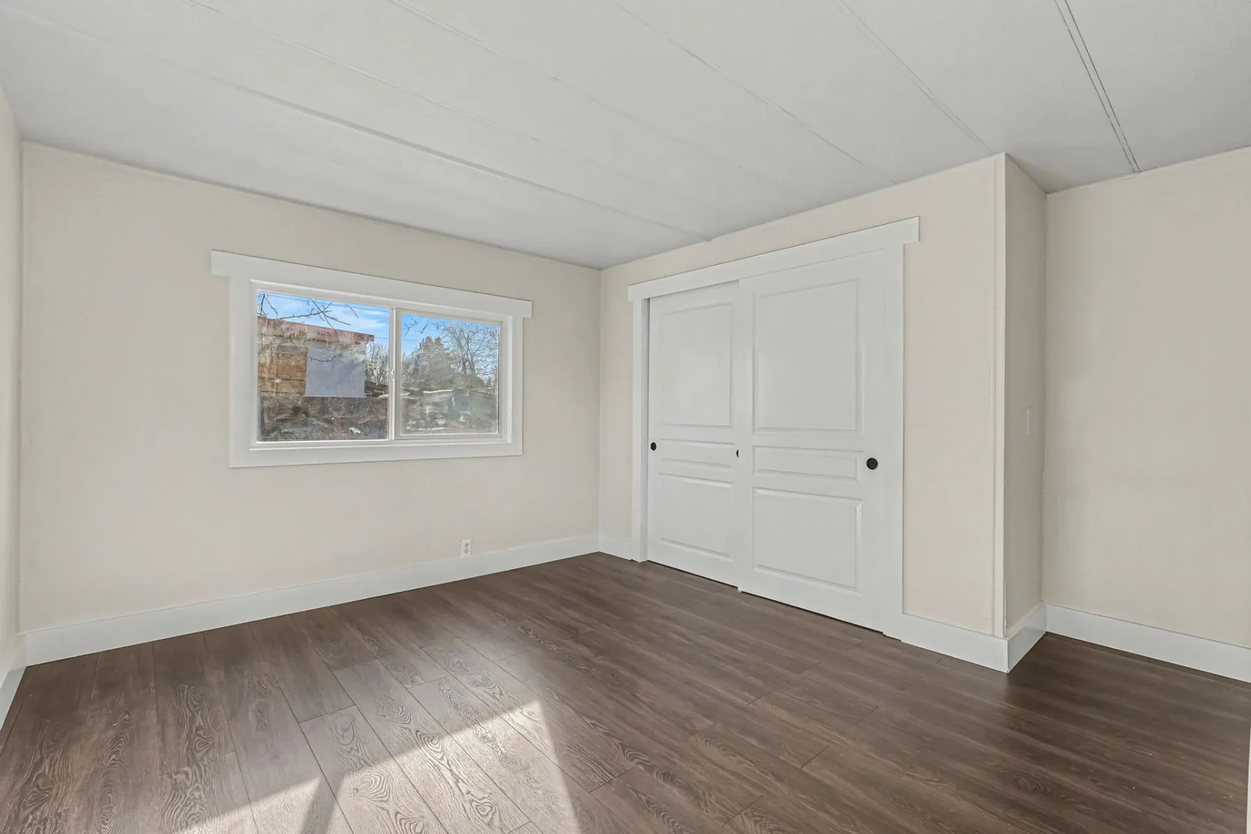 Bedroom with a window, sliding closet doors and wood-look plank flooring