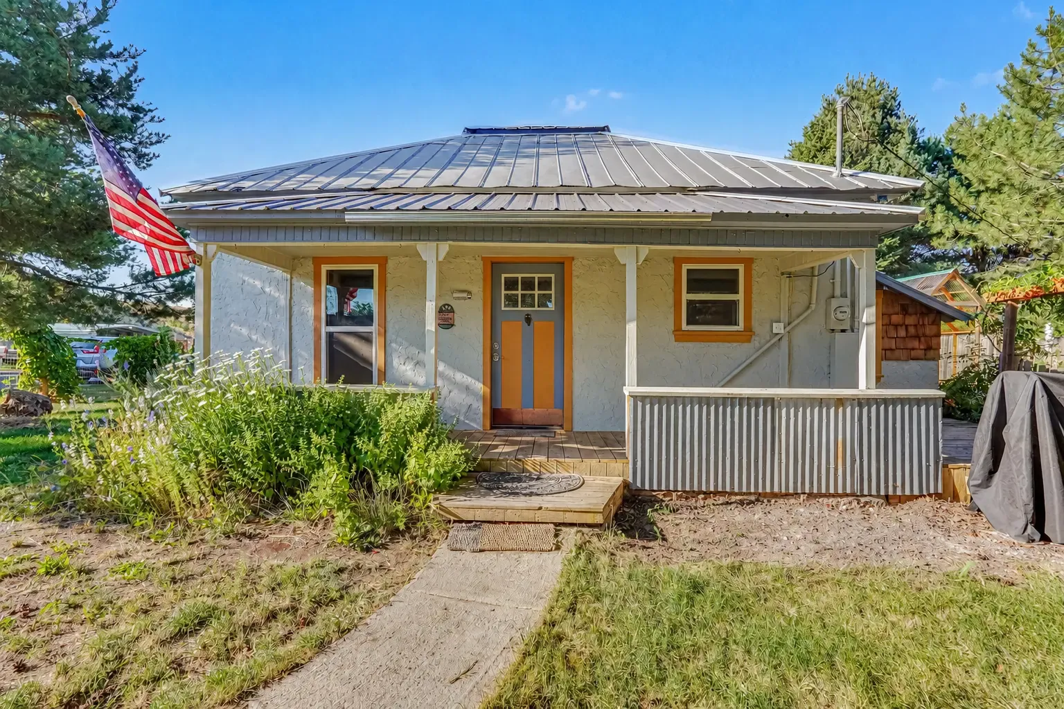 Front exterior of 130 N Weiser St, Midvale, Idaho, a single-level home with a metal roof, covered porch and American flag