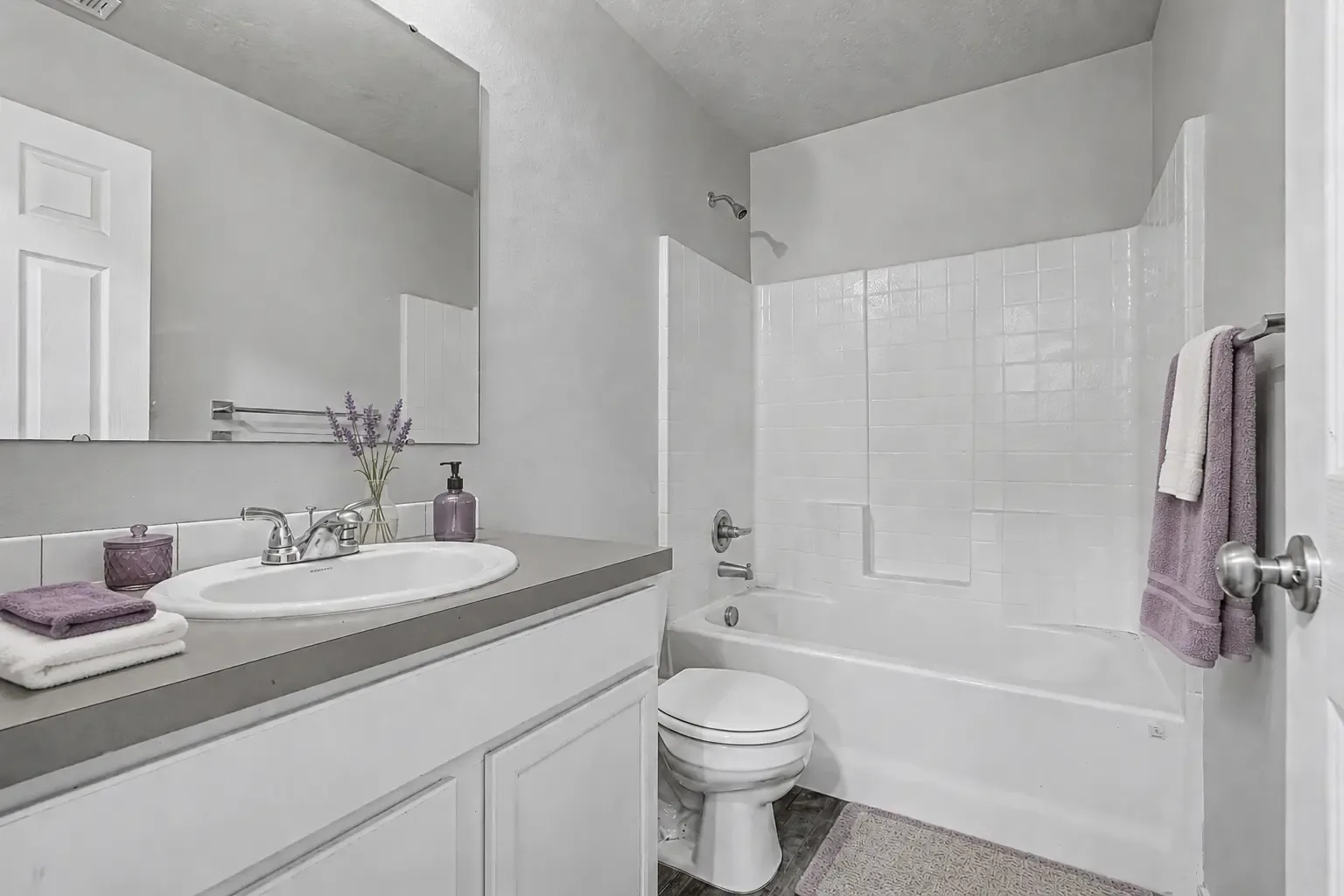 Second bathroom with a single-sink vanity, mirror and a tub with tiled shower surround