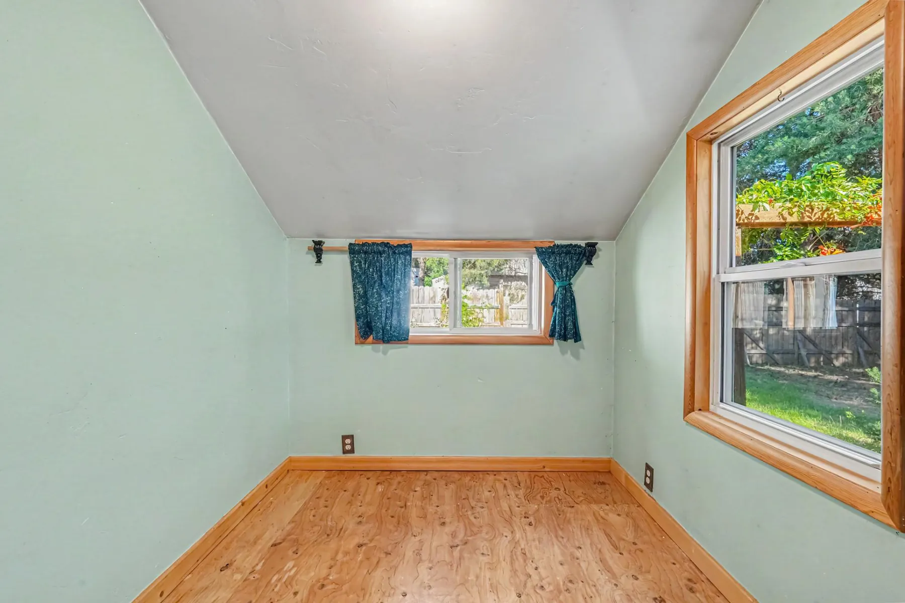 Flexible bonus room with two windows and wood plank flooring, suitable as a bedroom, office or hobby space