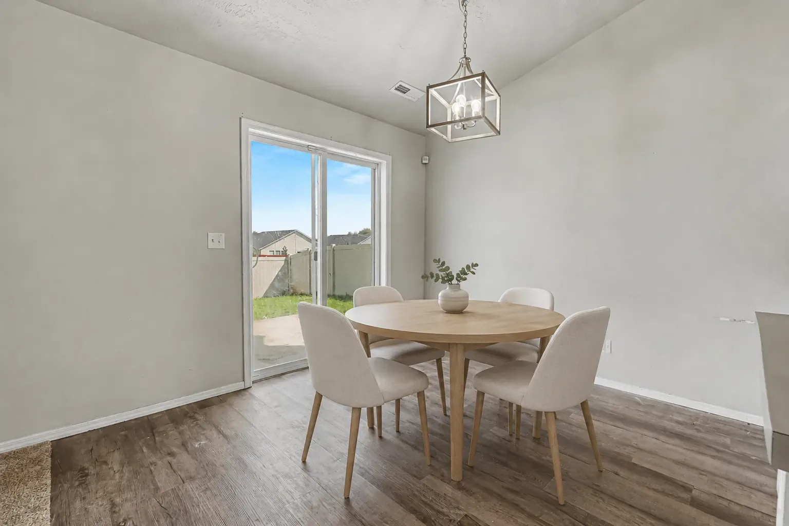 Dining area with a lantern-style light fixture and sliding glass door to the fenced backyard