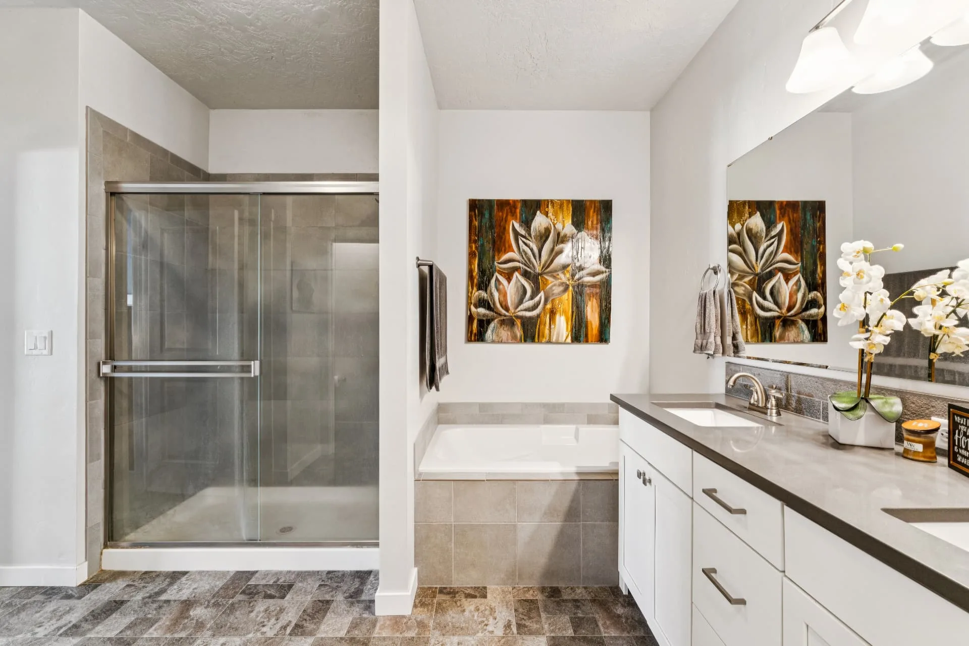 Primary bathroom with a tiled walk-in shower, separate soaking tub set in tile and a long vanity with dual sinks