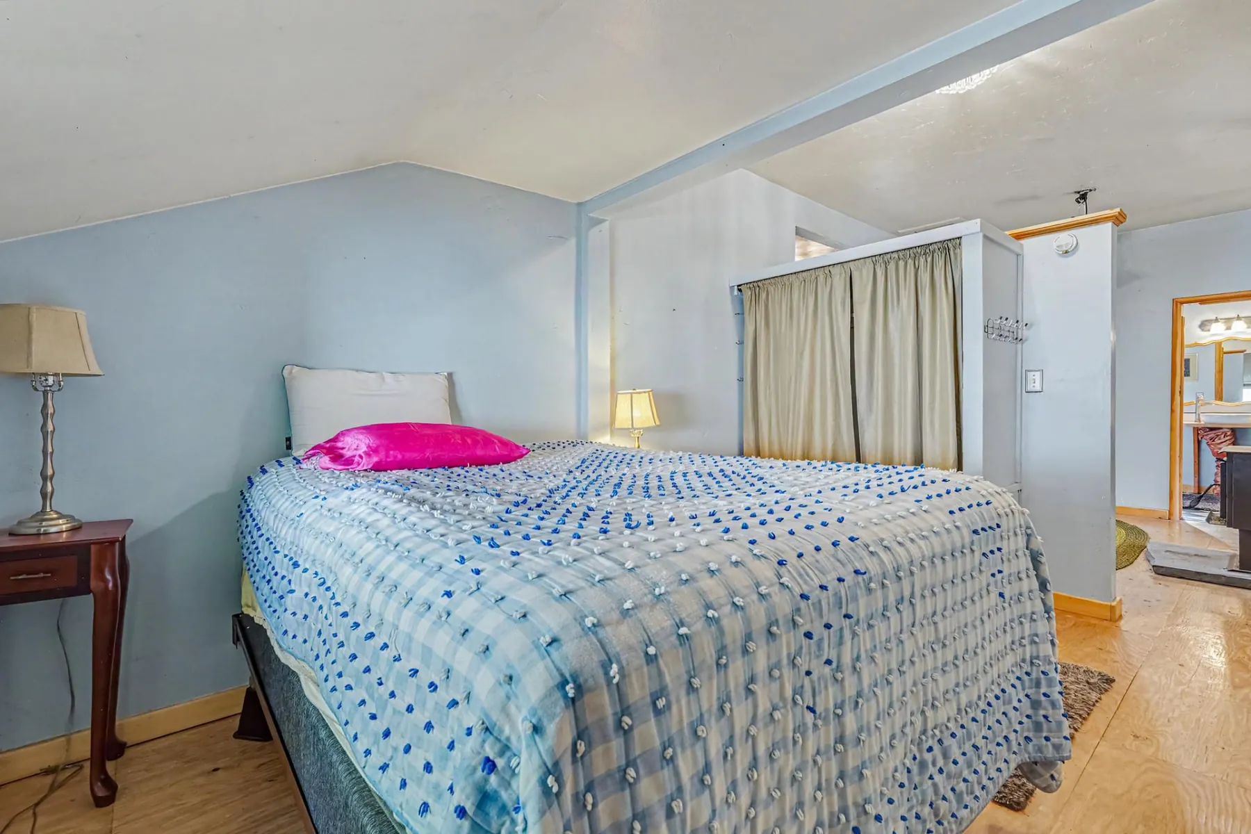Primary bedroom with a queen bed, vaulted ceiling and wood plank flooring