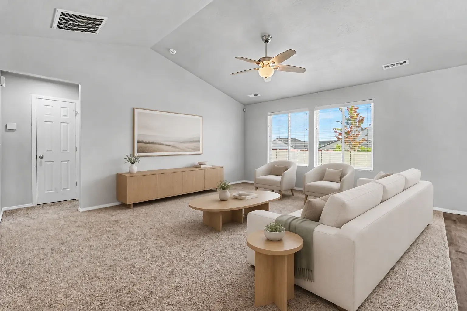 Living room with vaulted ceiling, ceiling fan, two windows with blinds and carpet